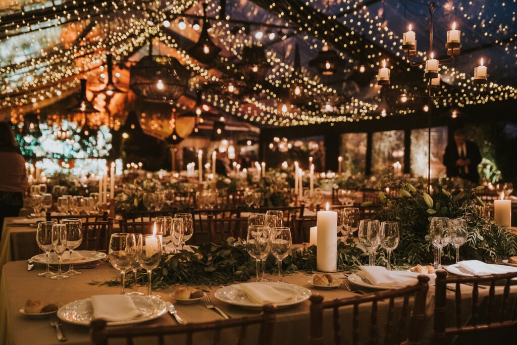 Table with plates, cutlery, glasses, flowers and candles with wooden chairs. Wedding decoration.